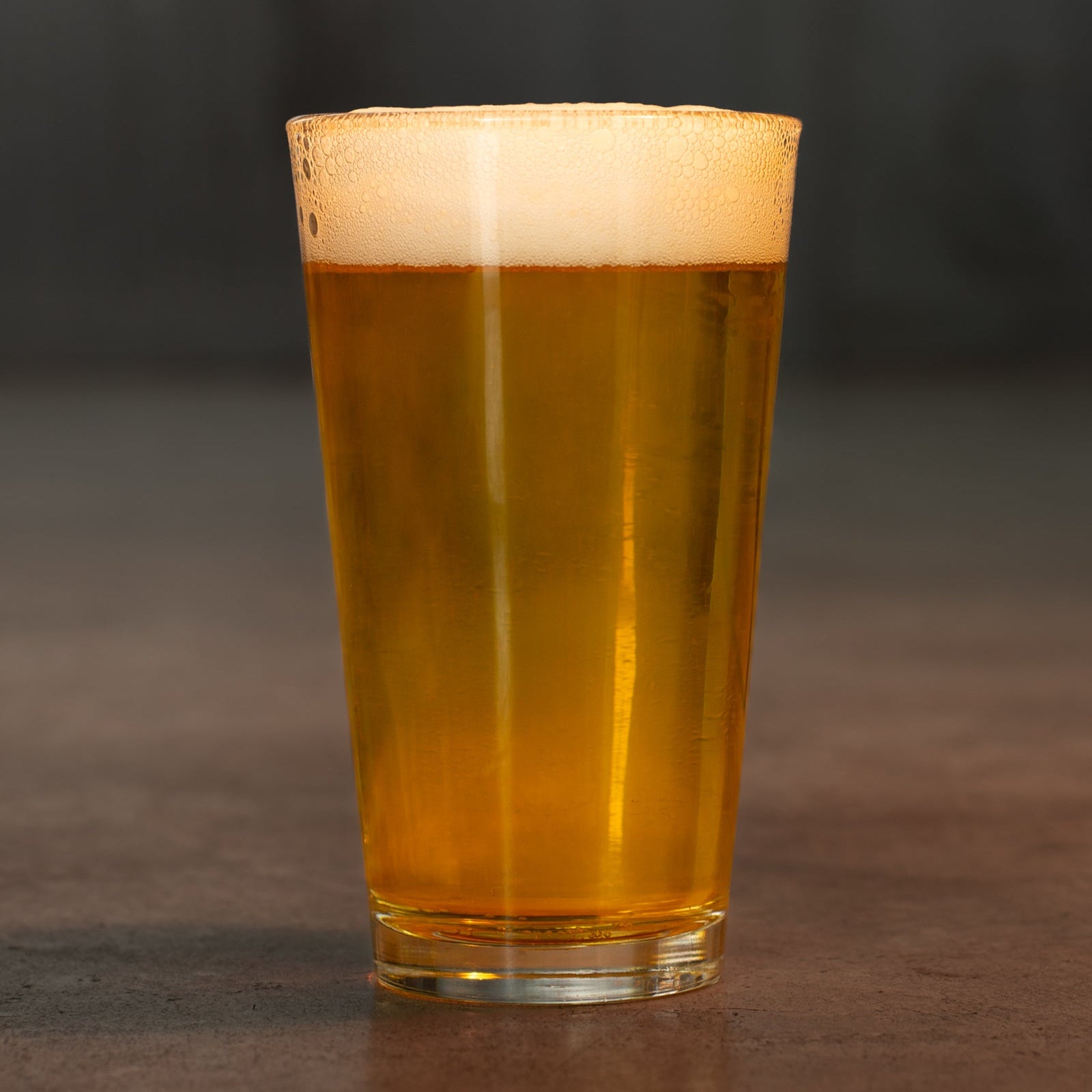 Pint of Roger's pilsner beer by Georgetown Brewing on the cement floor of the tasting room