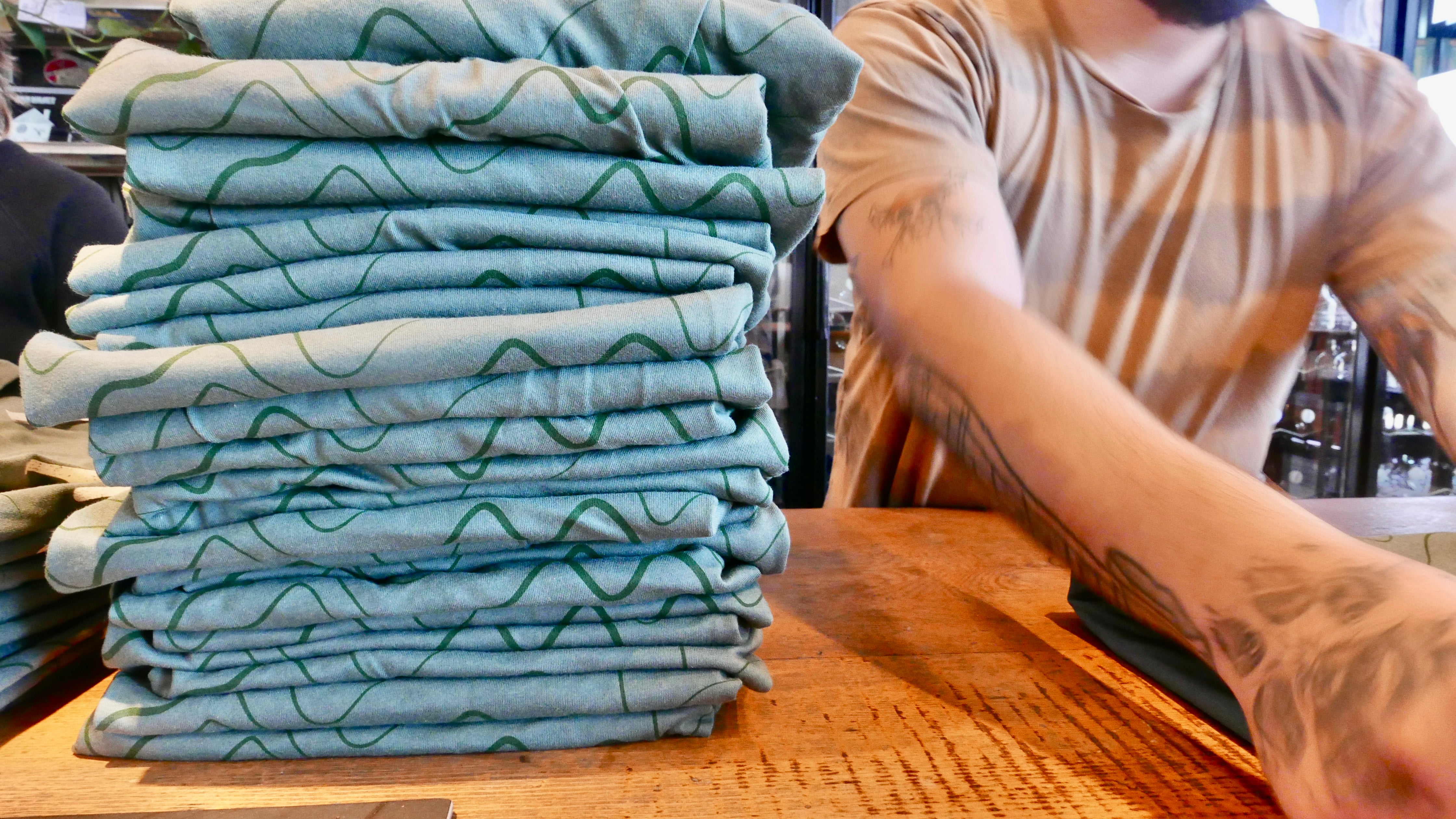 A stack of shirts is in the process of being folded by an employee