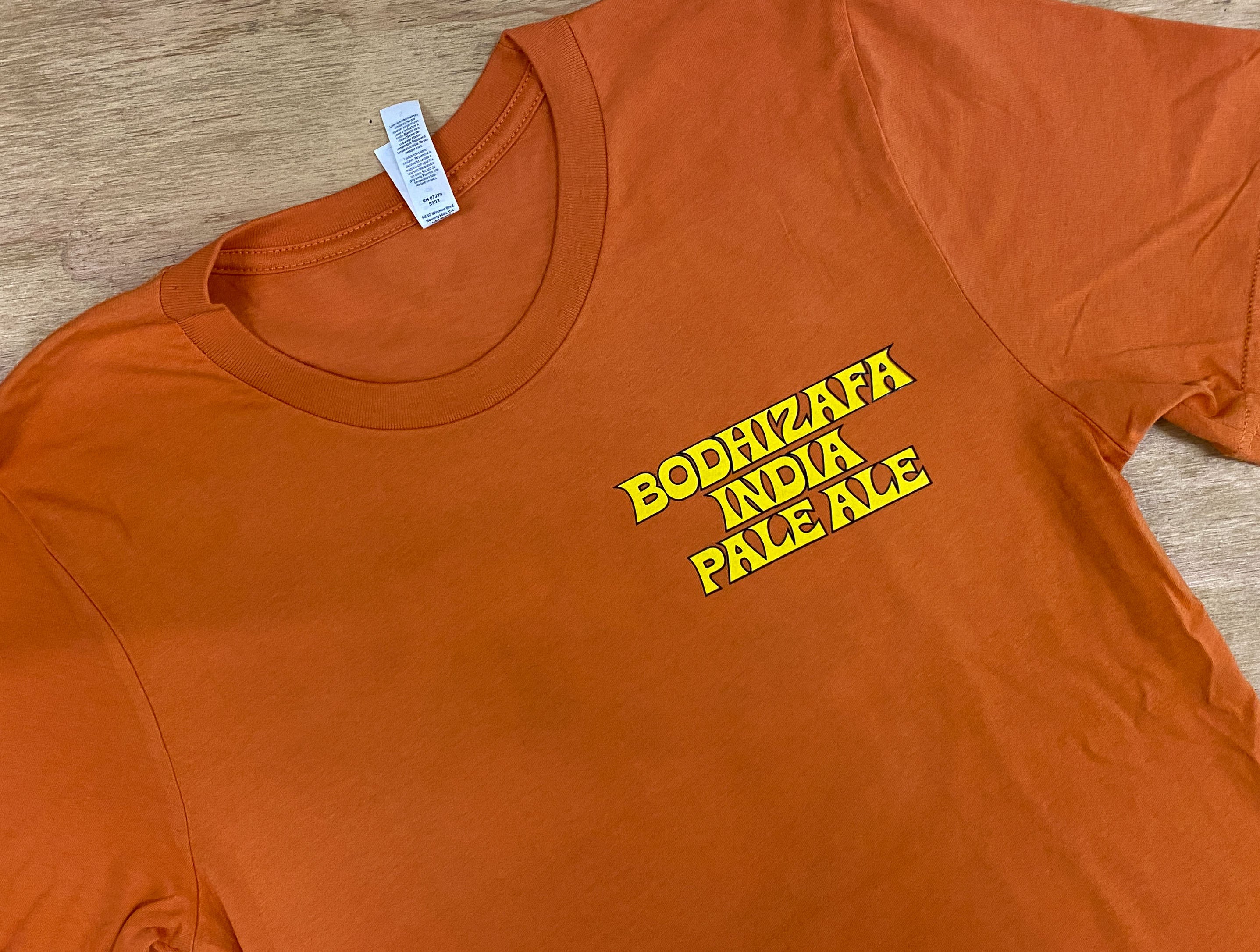 An orange Bella + Canvas t-shirt with 'BODHIZAFA INDIA PALE ALE' printed in yellow text on the front.