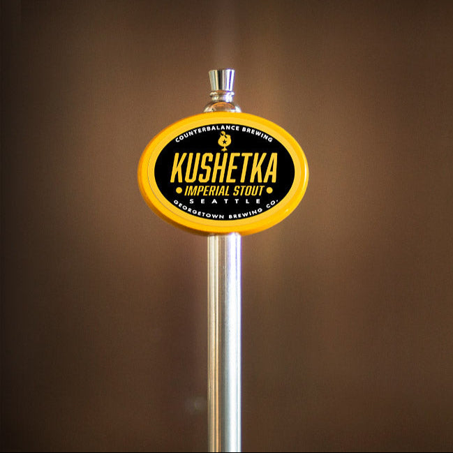 Kushetka Imperial Stout beer tap handle against a brown background