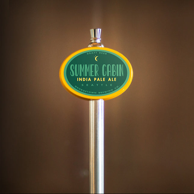 Tap handle with 'Summer Cabin India Pale Ale' label against a brown background