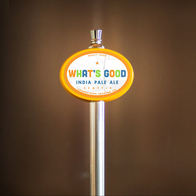 Beer tap with 'What's Good' India Pale Ale label against a brown background