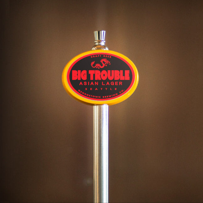 yellow oval tap handle with big trouble lager tap label