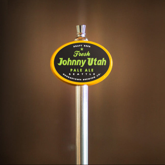 yellow oval beer tap handle with 'Johnny Utah' branding against a brown background