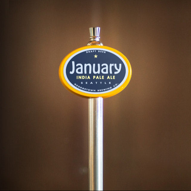 Beer tap handle with 'January India Pale Ale' label on a brown background