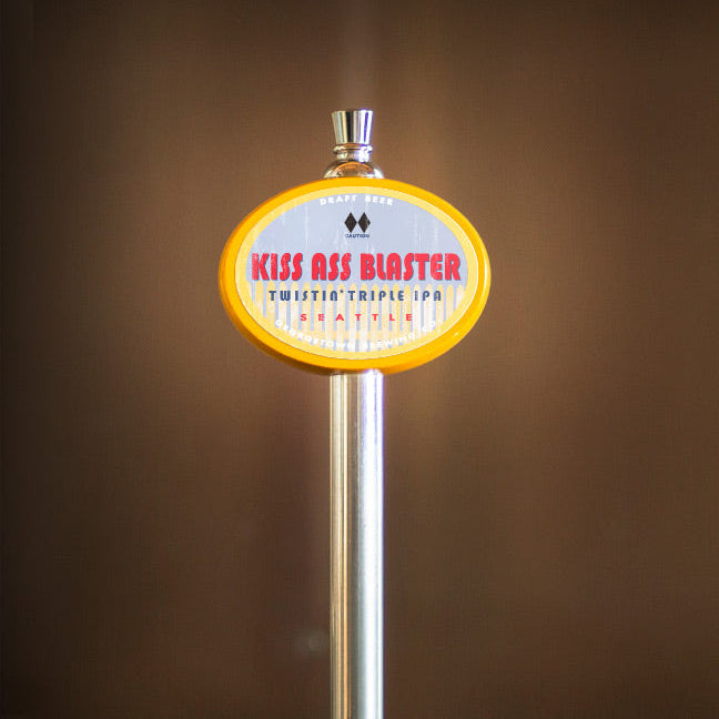 Beer tap handle with 'Kiss Ass Blaster' label against a brown background