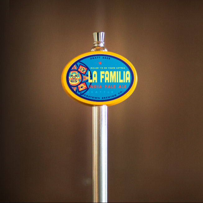beer tap handle with 'La Familia' branding against a brown background