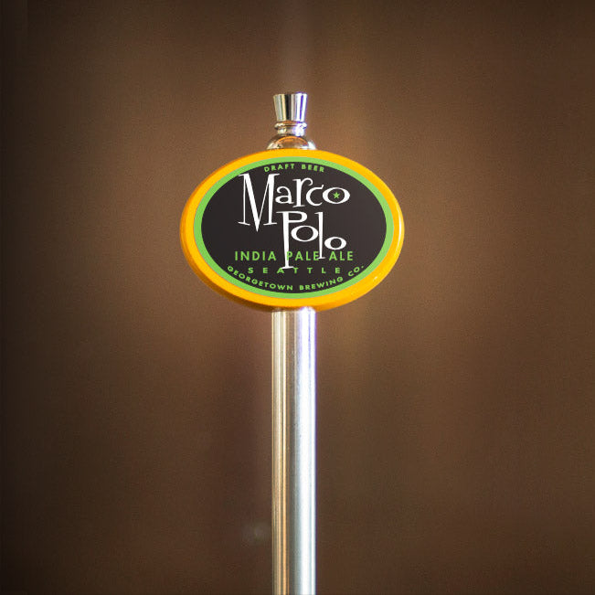 Beer tap handle with 'Marco Polo' label against a blurred brown background