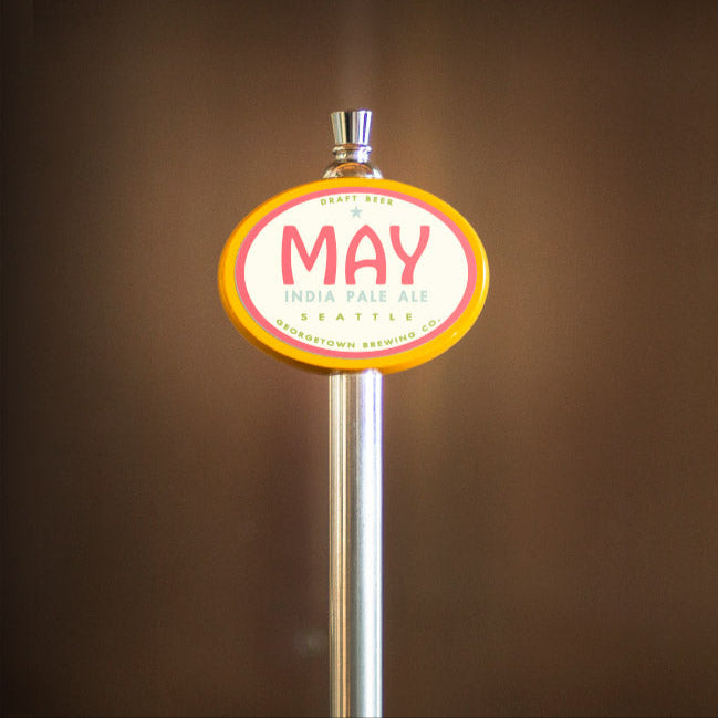 Beer tap handle with 'May' label against a blurred background