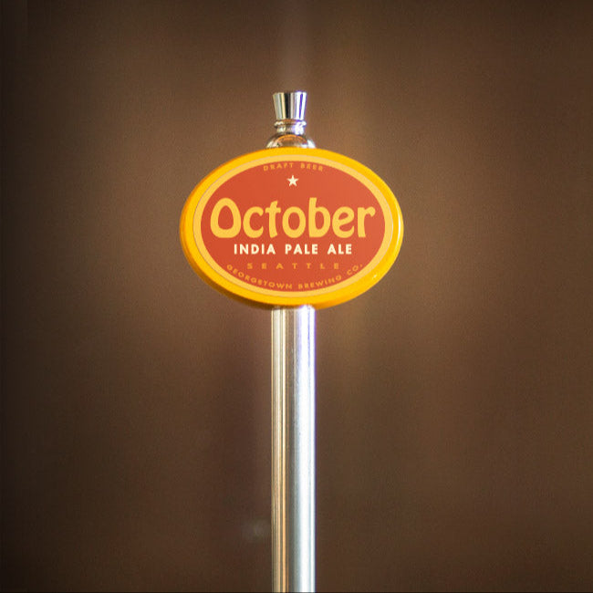Beer tap handle with 'October India Pale Ale' label on a brown background