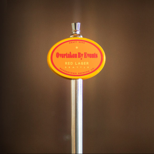 beer tap handle with red and yellow Overtaken by events label on a brown background
