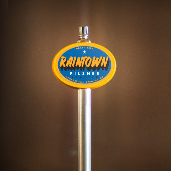Raintown Pilsner beer tap handle against a brown background