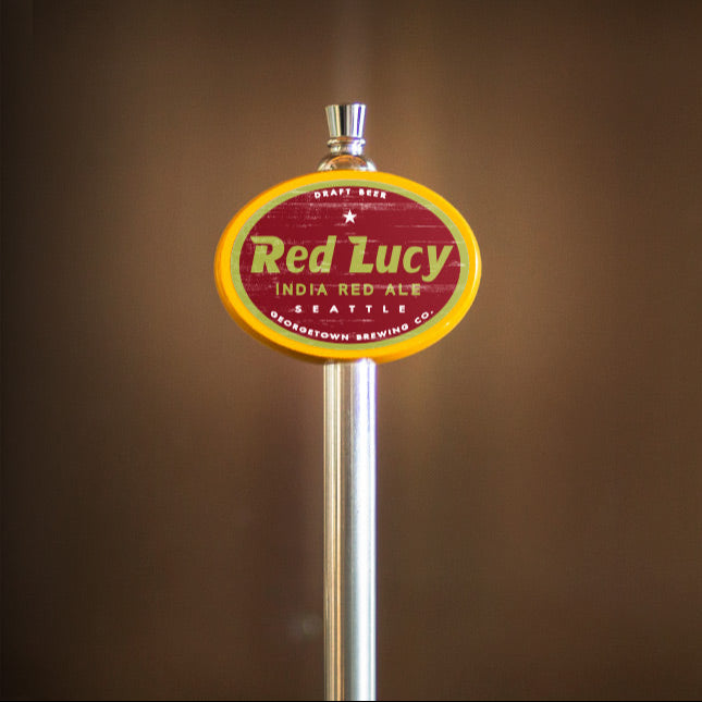 Red Lucy India Pale Ale tap handle against a brown background