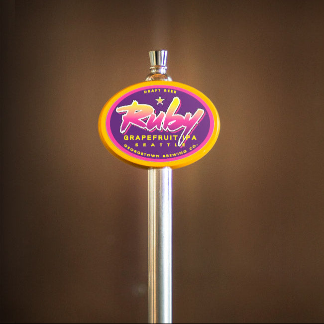 Beer tap handle with a colorful Ruby IPA label on a brown background