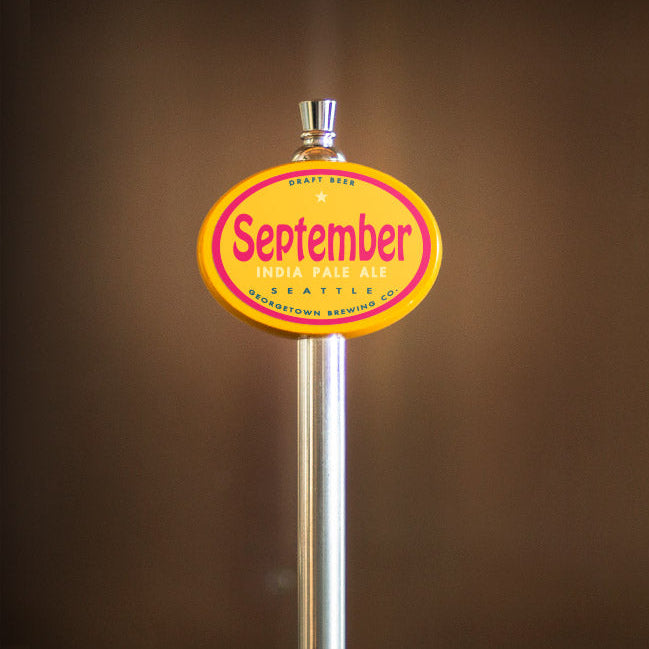 Beer tap handle with 'September' label on a blurred brown background