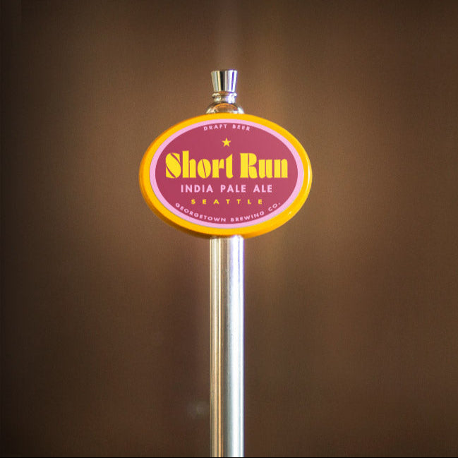 Beer tap handle with 'Short Run' label against a brown background