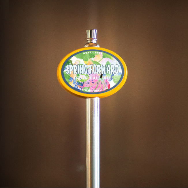 beer handle with a colorful sign featuring floral designs and the name Spring Forward on a brown background