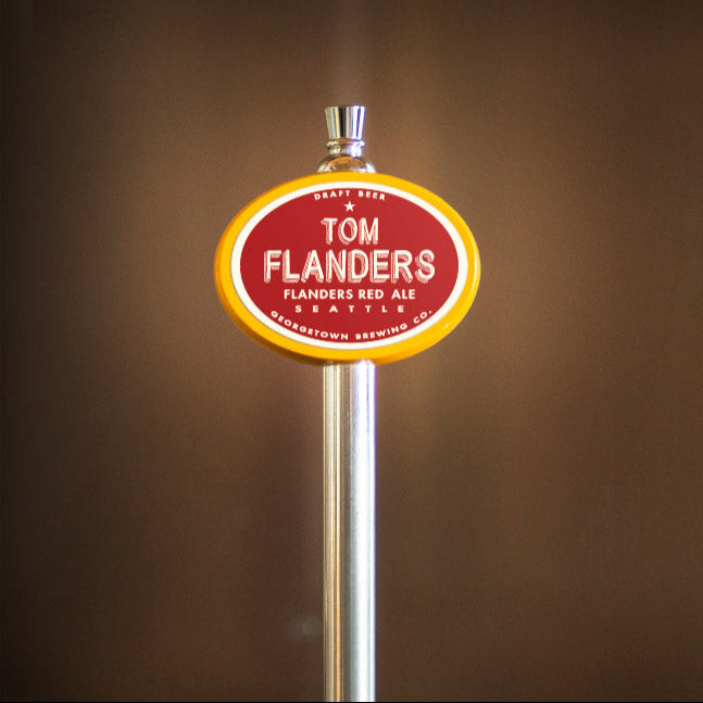 Tom Flanders beer tap handle against a brown background