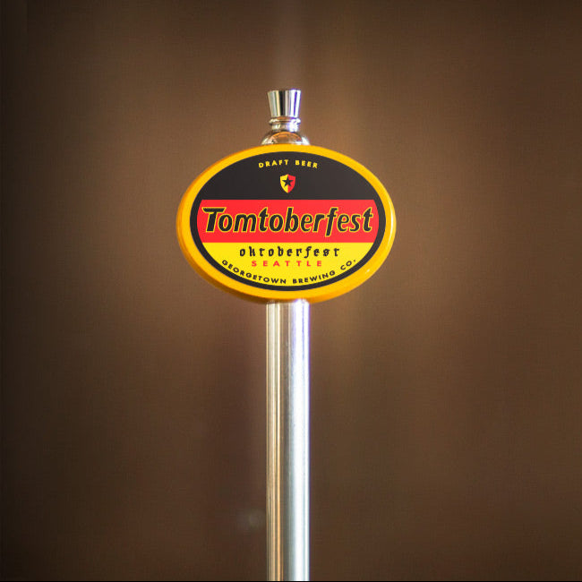 Beer tap handle with a 'Tomtoberfest' label against a brown background