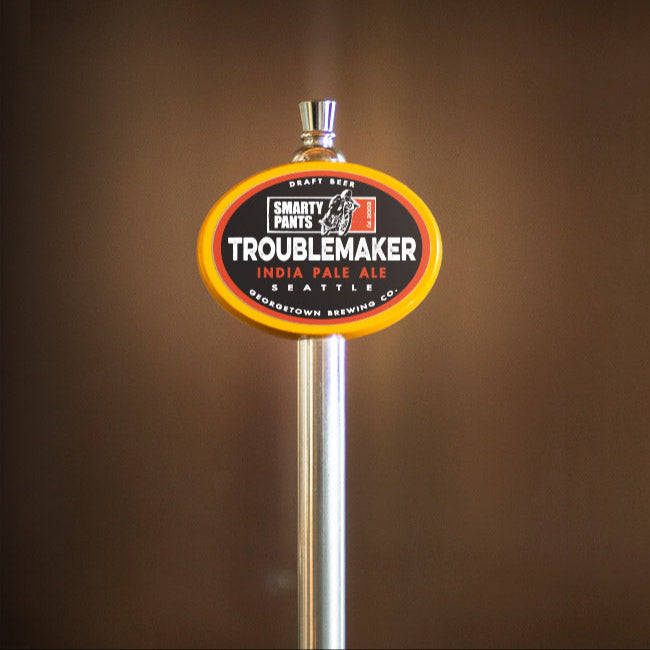 Beer tap handle with 'Troublemaker' label against a brown background