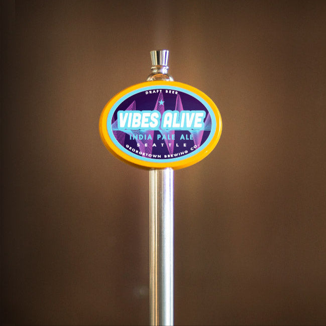 Beer tap handle with 'Vibes Alive' label against a brown background