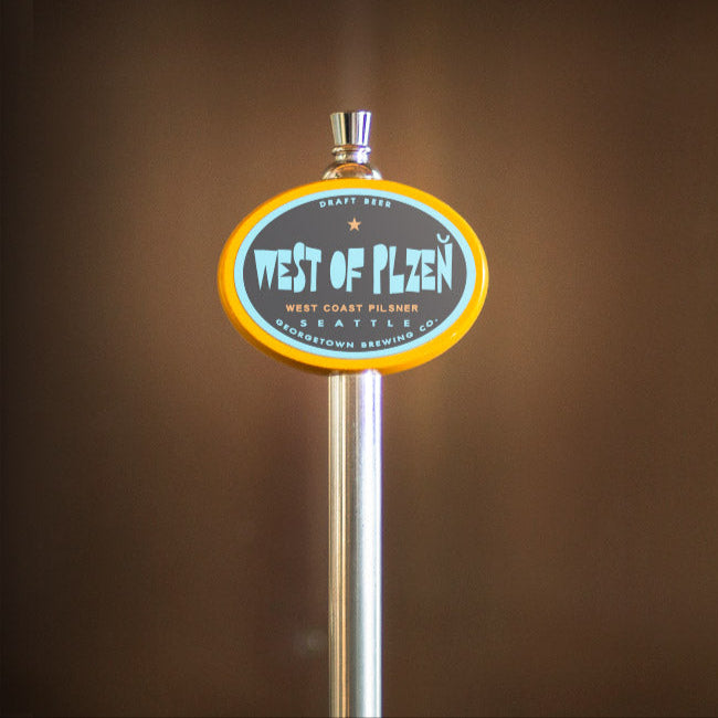 Metallic beer tap handle with 'West of Plzen' branding against a blurred brown background