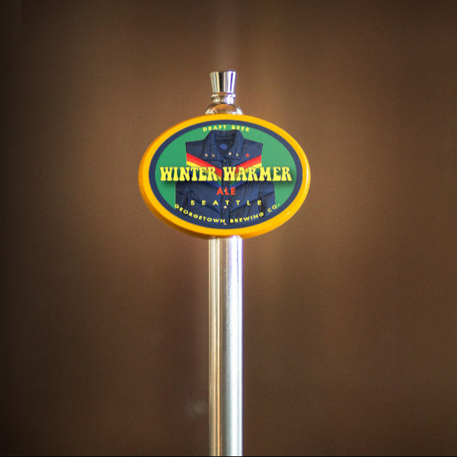 beer tap handle with a colorful Winter Warmer label on a brown background