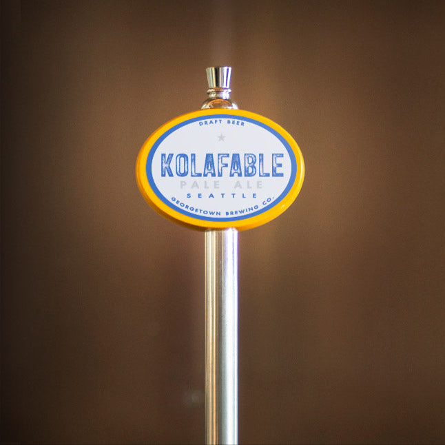 beer tap handle with 'Kolafable' branding against a blurred background