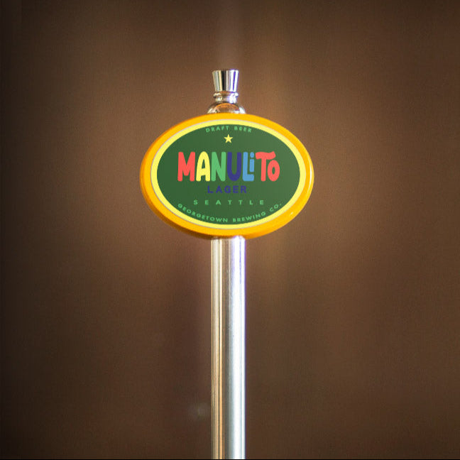 Manuelito beer tap handle with a colorful label on a brown background