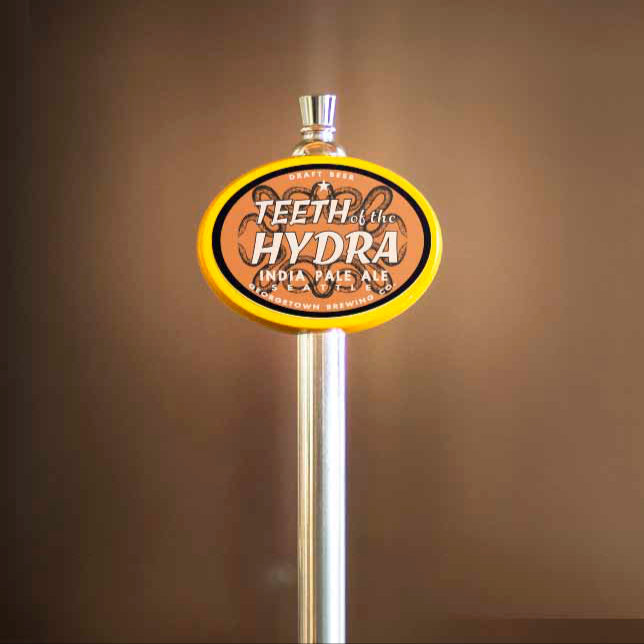 Beer tap handle with 'Teeth of the Hydra' branding on a brown background