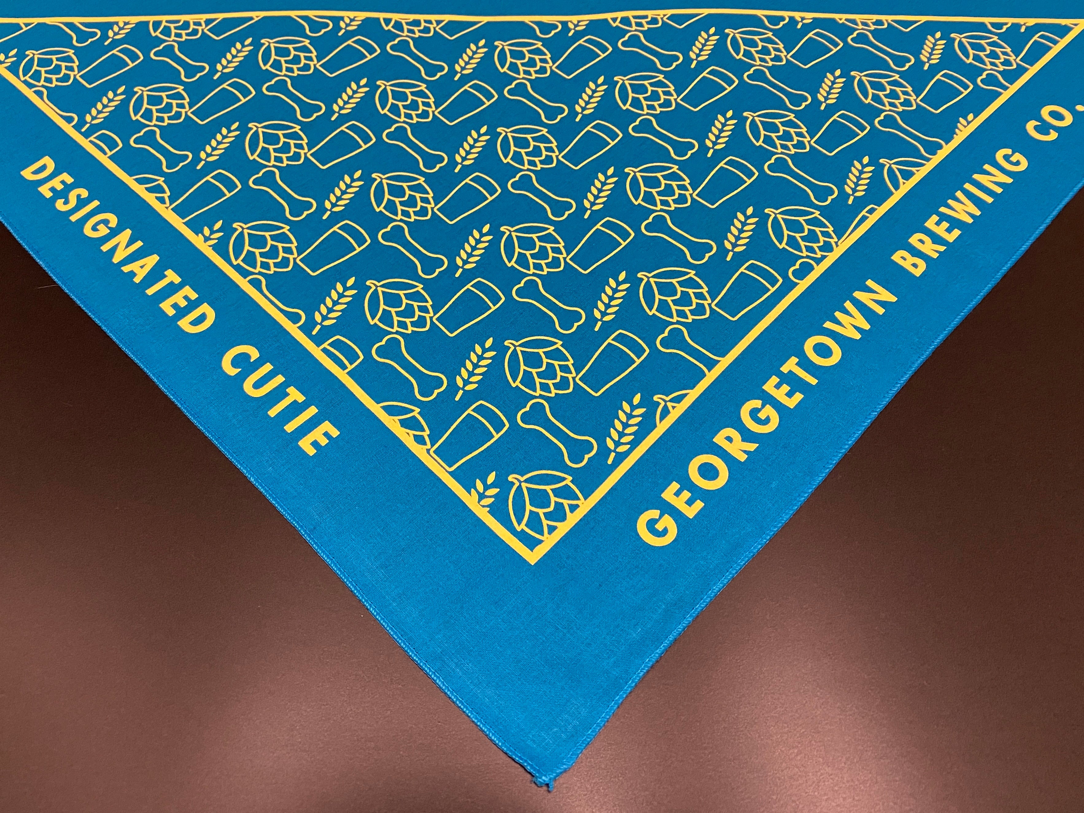 Blue bandana with yellow designs and text reading Designated Cutie Georgetown Brewing Co