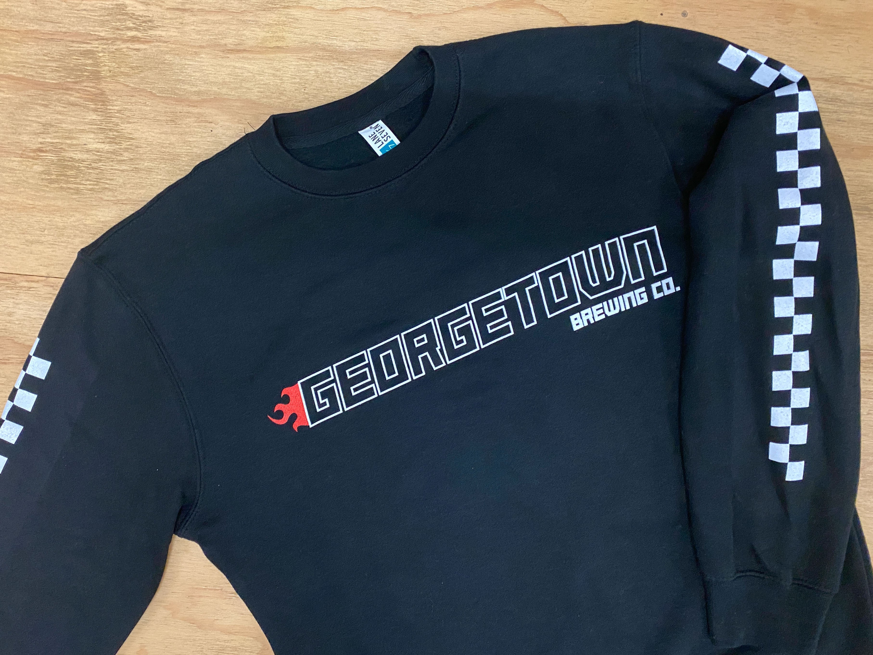 Black long-sleeve shirt with Georgetown Brewing Co. logo in a Nascar style font. Sleeves have checkered band down them.