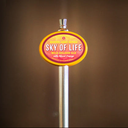 Beer tap handle with 'Sky of Life' label against a pink background