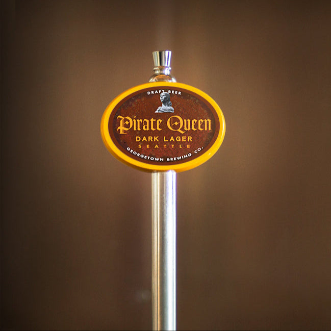 Pirate Queen Dark Lager tap handle against a brown background