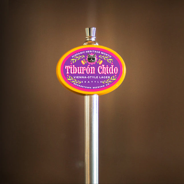 yellow tap handle oval with a little cat face wearing sunglasses that says Tiburon Chido which means Cool or Rad Shark