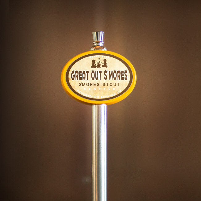 Beer tap handle with 'Great Out Smores Stout' label against a brown background