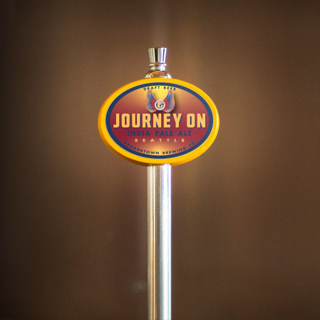 Beer tap handle with 'Journey On' label against a brown background