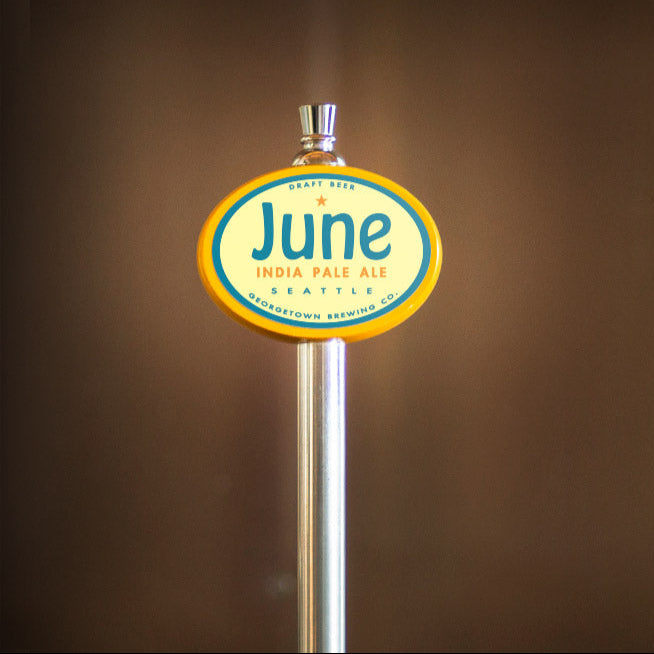 June India Pale Ale tap handle on a blurred brown background