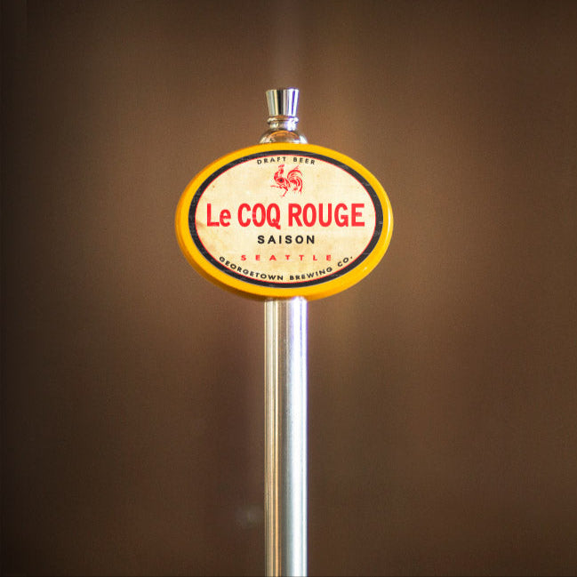 Le Coq Rouge beer tap handle against a brown background