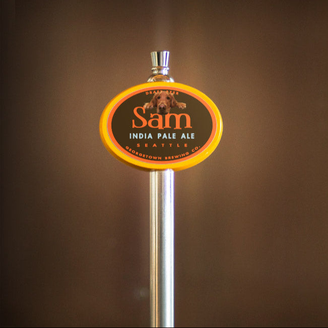Beer tap handle with 'Sam' India Pale Ale label on a blurred background