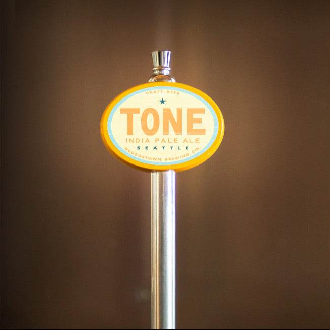 Tone beer tap handle against a brown background