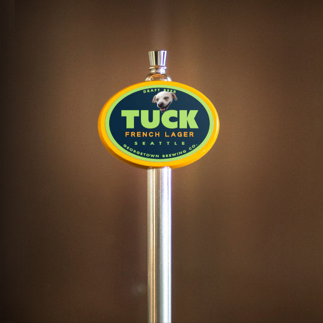 Tuck French Lager beer tap handle on a brown background