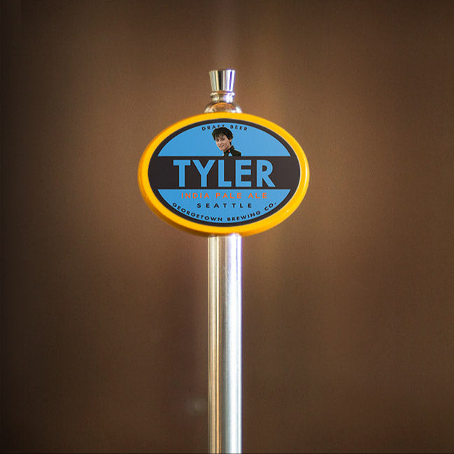 Beer tap handle with 'Tyler' branding against a brown background