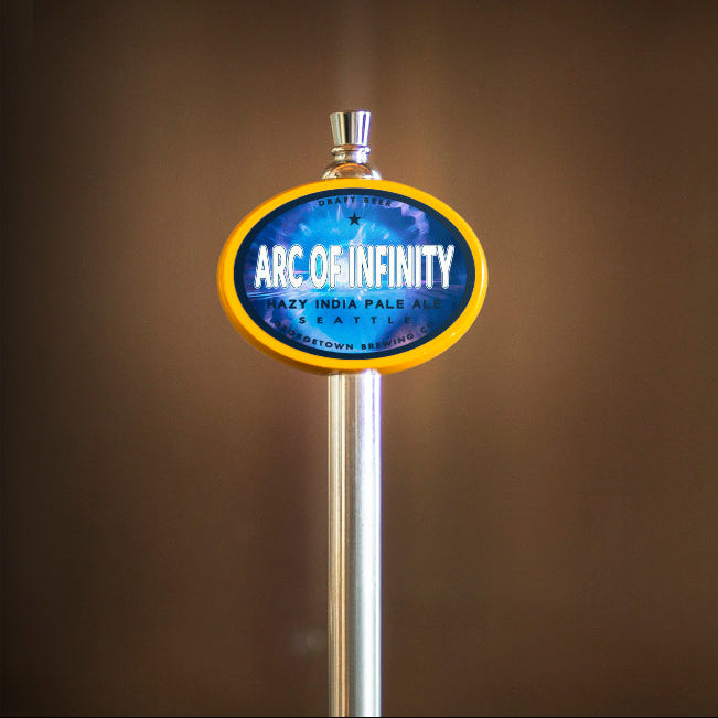 Beer tap handle with 'Arc Of Infinity' branding against a brown background