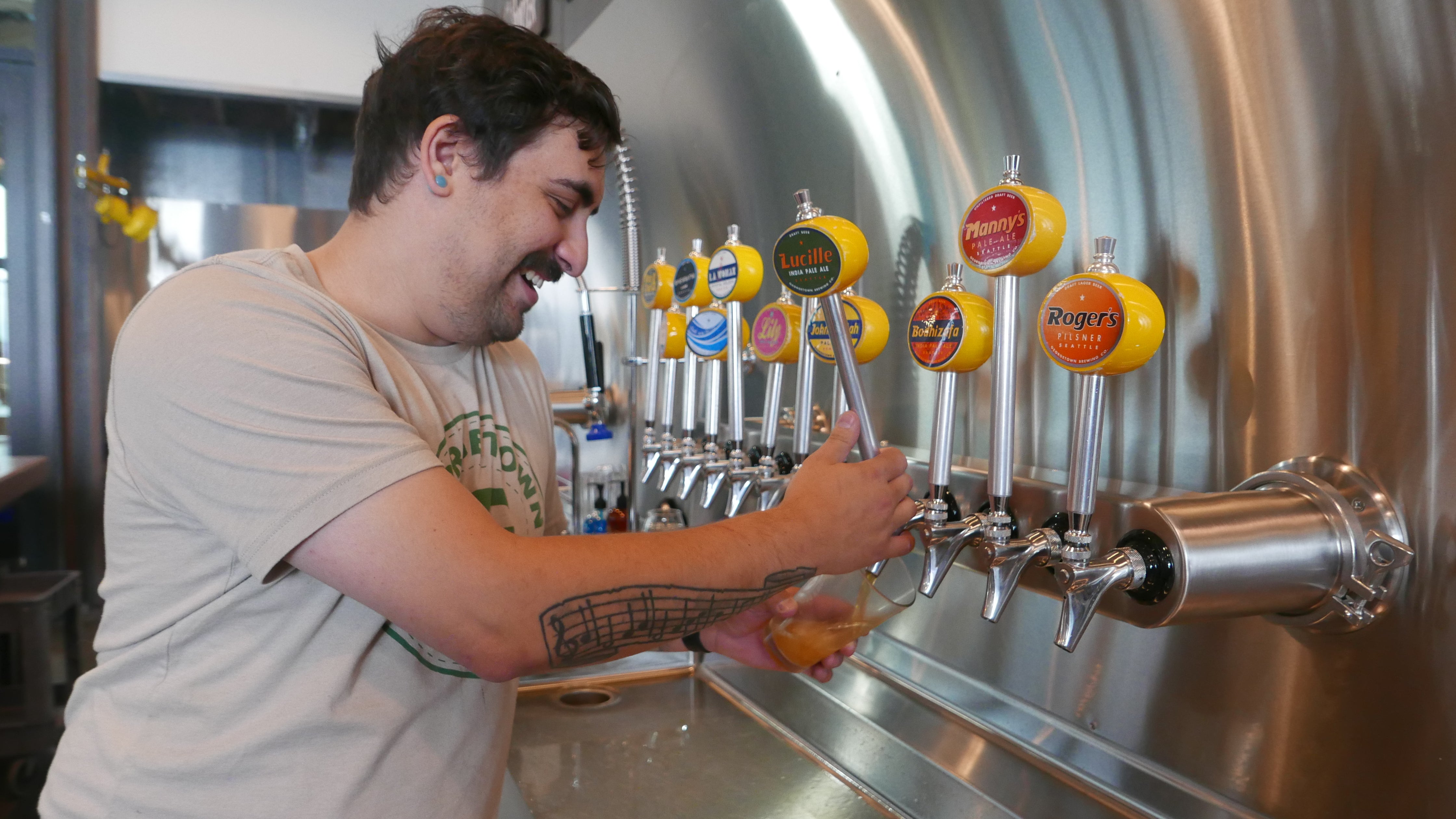 A man with dark hair and moustache pours a beer off the tap