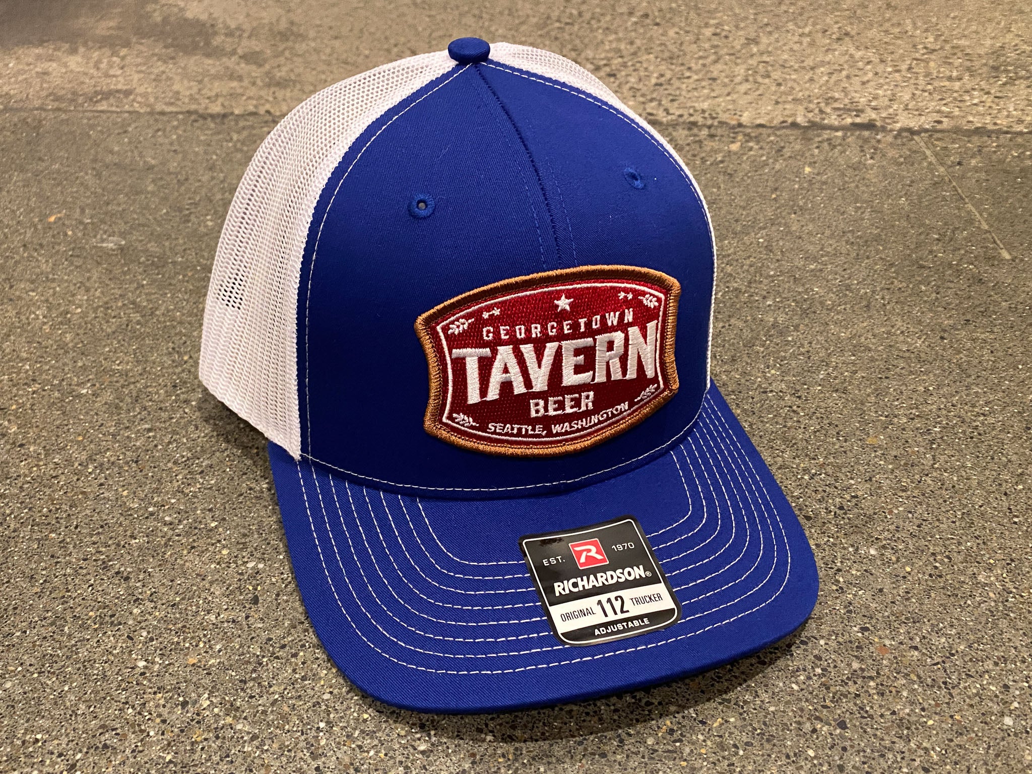 a blue and white trucker hat with a red, white and gold patch that says Georgetown Tavern Beer Seattle WA
